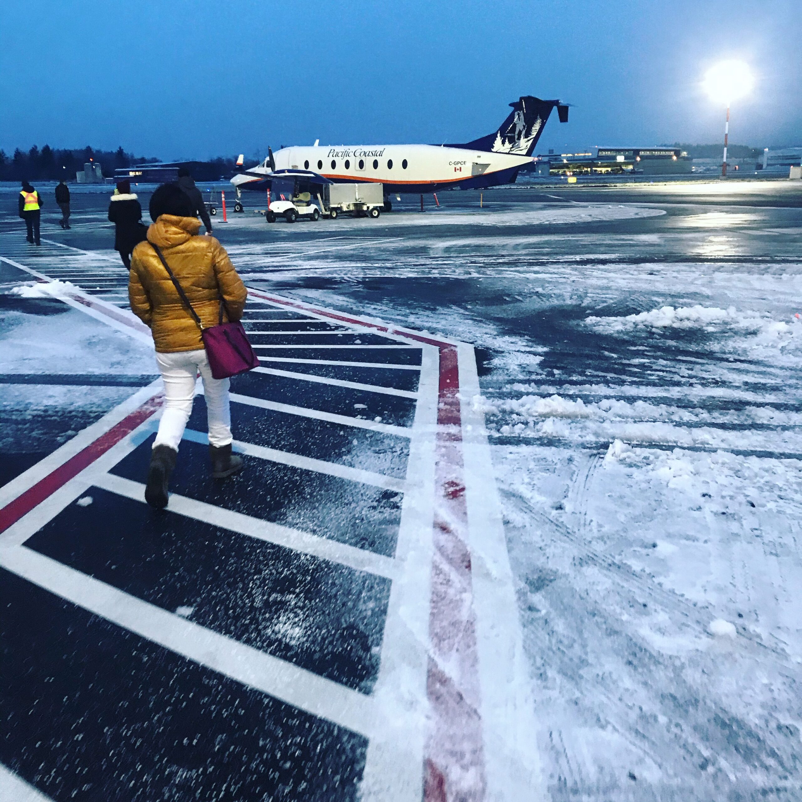 Pacific Coastal Airlines plane parked on snowy tarmac at night