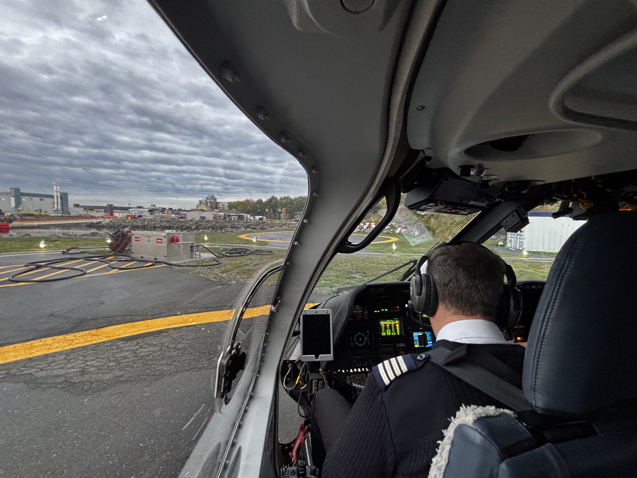 View from behind Helijet pilot looking through cockpit windshield at helipad